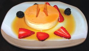 Caramel custard flan, finished with sugar glass, berries and a liquid caramel sauce. Photo by Rico Cassoni