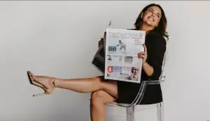 Realtor reading the Coast News while seated in a chair