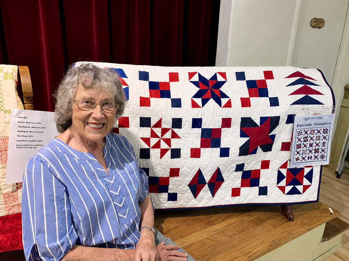 Master quilter Eleanor Burns poses with a patriotic Fourth of July-themed quilt in 2024 at her Julian studio, where she teaches quilting classes to local students. Courtesy photo