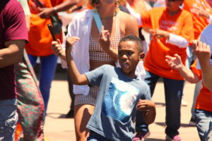 A young boy in a blue shirt plays an air guitar.