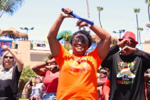 A woman in an orange shirt smiles and dances.