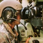 Soldier operating advanced electronic optics equipment inside a military vehicle.