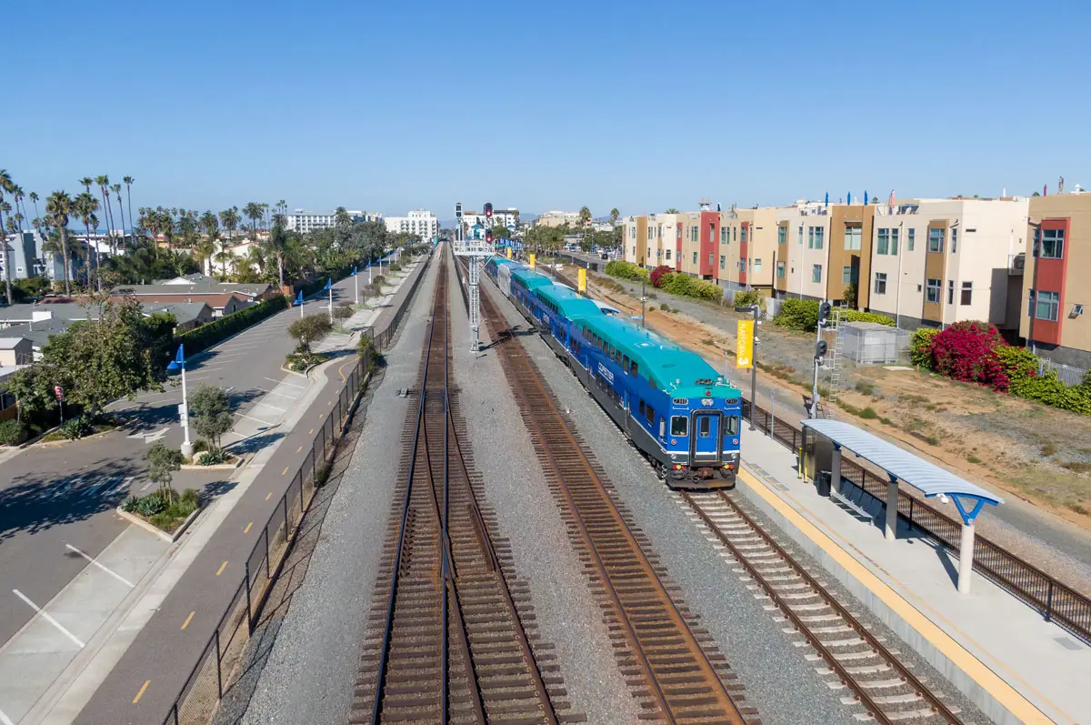 A Sprinter train travels through Oceanside near residential development. Under Senate Bill 79, cities must allow additional housing opportunities near designated transit stations, although local governments may defer or exempt certain sites. Photo by Oak City Drone