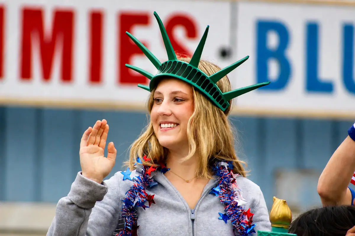 A girl waves to the crowd while wearing a green Statue of Liberty foam crown on June 27 during the 2026 Oceanside Independence Day Parade. Photo by Samantha Nelson