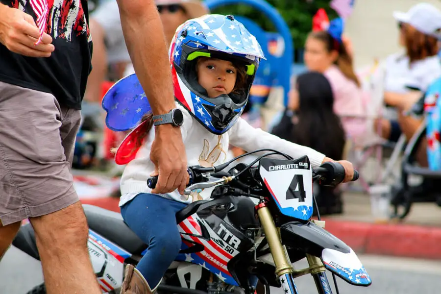 A young motorcyclist wearing a helmet rides along Coast Highway during the 2026 Oceanside Independence Day Parade on June 27. Photo by Samantha Nelson