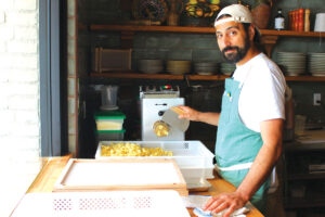 Pastaria Vivi Chef de Cuisine Harrison Axelrod uses the pasta extruder to create campanelle pasta at the restaurant on N. El Camino Real in Encinitas. Photo by Rico Cassoni