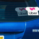 A vehicle displays rideshare decals for Uber and Lyft. A statewide ballot measure would expand rideshare company liability and impose new safety requirements. Photo by Sundry Photography