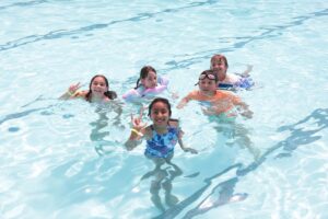 Five kids smiling in a pool