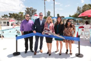Five city officials stand in front of a ribbon at a pool