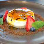 Cheesecake de Maracuyá, a silky passion fruit cheesecake topped with passion fruit syrup, berries, mint, and graham crumble. Photo by Rico Cassoni