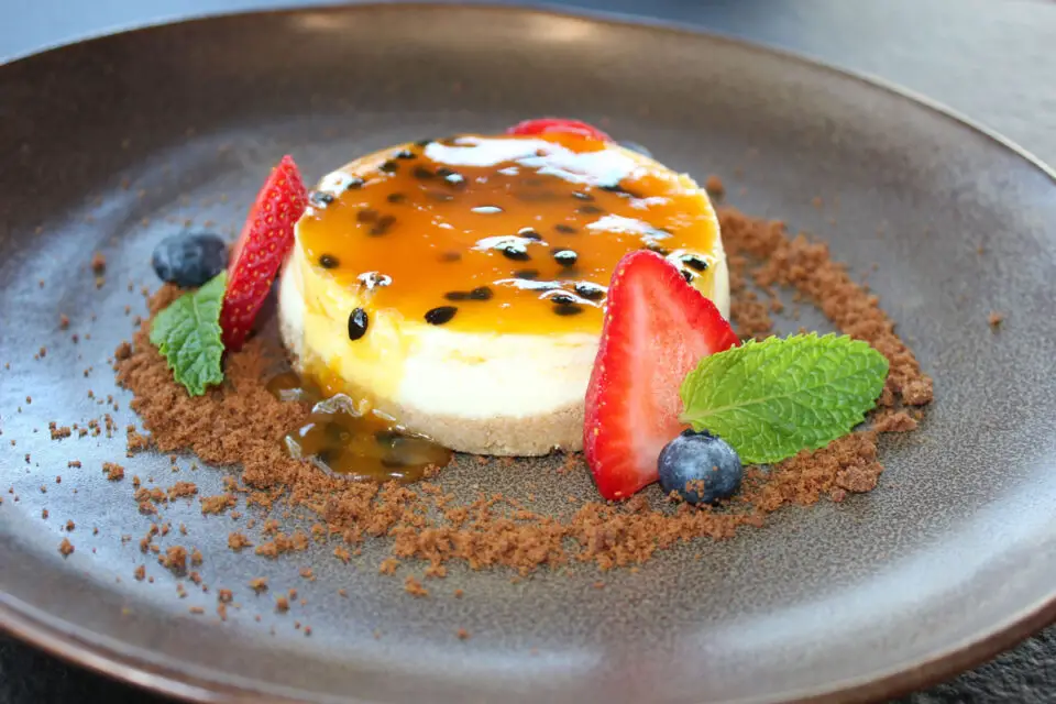 Cheesecake de Maracuyá, a silky passion fruit cheesecake topped with passion fruit syrup, berries, mint, and graham crumble. Photo by Rico Cassoni