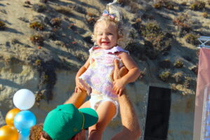 A man holds a young girl up in the aiir