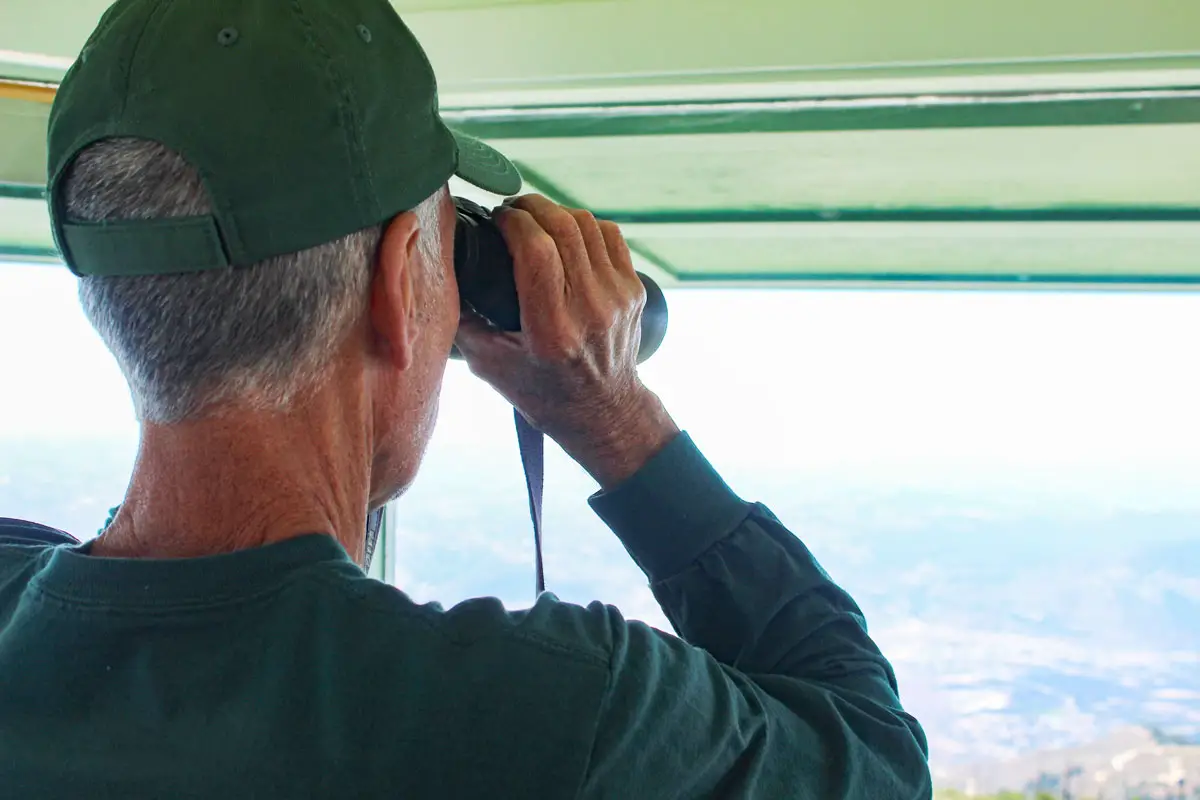 Bob Littlejohn, a Valley Center resident and volunteer with the Forest Fire Lookout Association, watches smoke rise from Camp Pendleton on July 3 from his view at Boucher Hill Lookout Tower on Palomar Mountain. Photo by Samantha Nelson