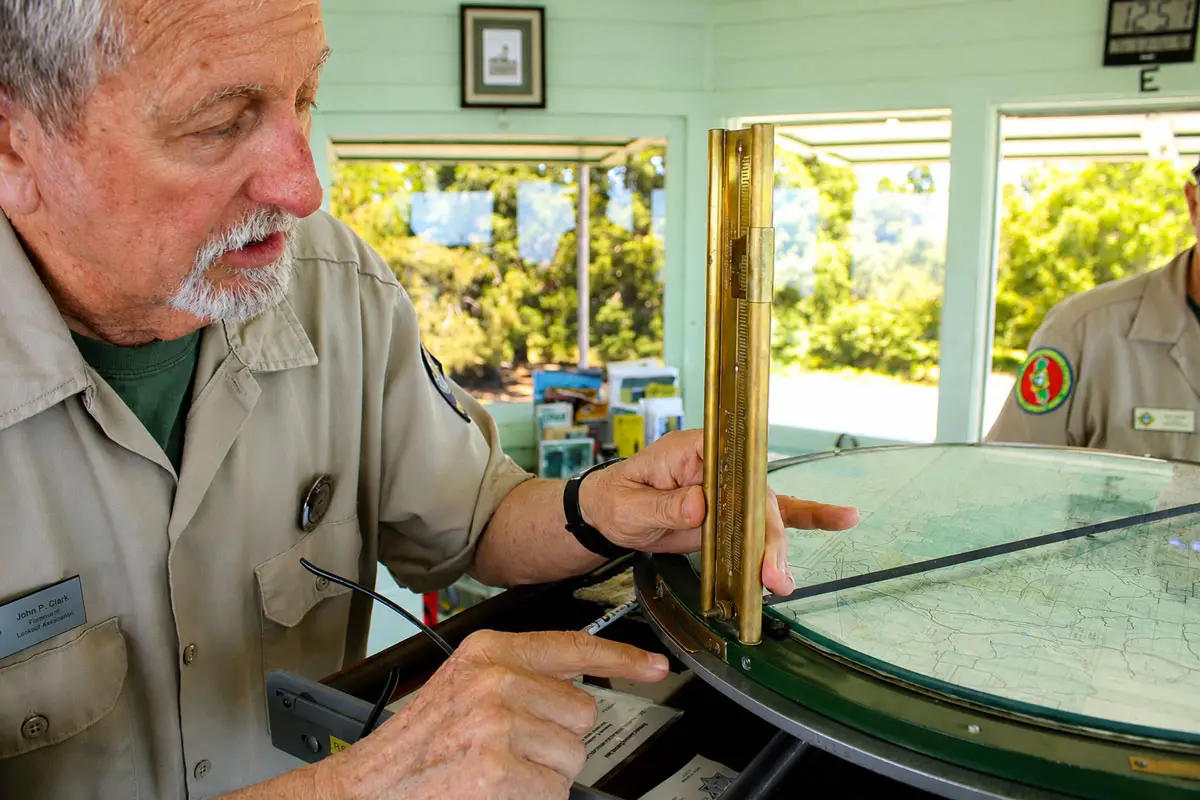 fire volunteer John Clark uses a 1930s-era Osborne Fire Finder to pinpoint a fire’s location on July 3 at the Boucher Hill Fire Lookout. Photo by Samantha Nelson