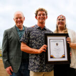 Quade Kelley, winner of The Coast News Teen Writing Contest, Encinitas Mayor Bruce Ehlers and contest sponsor Melissa Huk of Ms. Oceanside Real Estate smile for a photo on July 9 at the Encinitas Library. Photo by Jordan P. Ingram