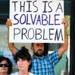 Residents hold signs calling for safer streets during a July 21 rally outside Encinitas City Hall. Safe Streets Encinitas organized the event to urge city leaders to improve traffic and pedestrian safety. Photo by Samantha Nelson