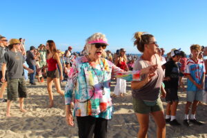 A woman in bright clothes dances on the beach