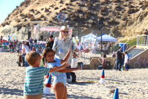 Children play with giant bubbles on the beach