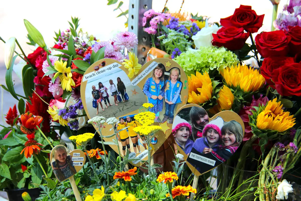 Photos of Seraphina Rose Fadick with friends and members of Girl Scouts Troop 1258 are displayed on July 14 at a roadside memorial in Encinitas. Photo by