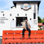 Sip-N-Sea owner Giuseppe Georgees sits on orange construction barriers installed in front of his walk-up shop along North Coast Highway 101 in Leucadia. Photo by Summer Hu