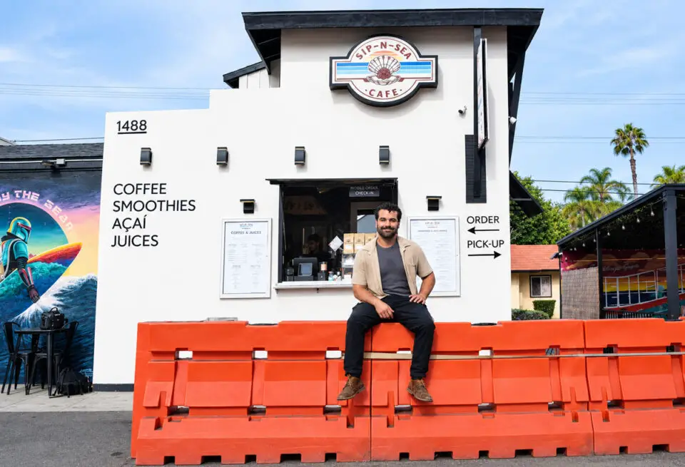 Sip-N-Sea owner Giuseppe Georgees sits on orange construction barriers installed in front of his walk-up shop along North Coast Highway 101 in Leucadia. Photo by Summer Hu