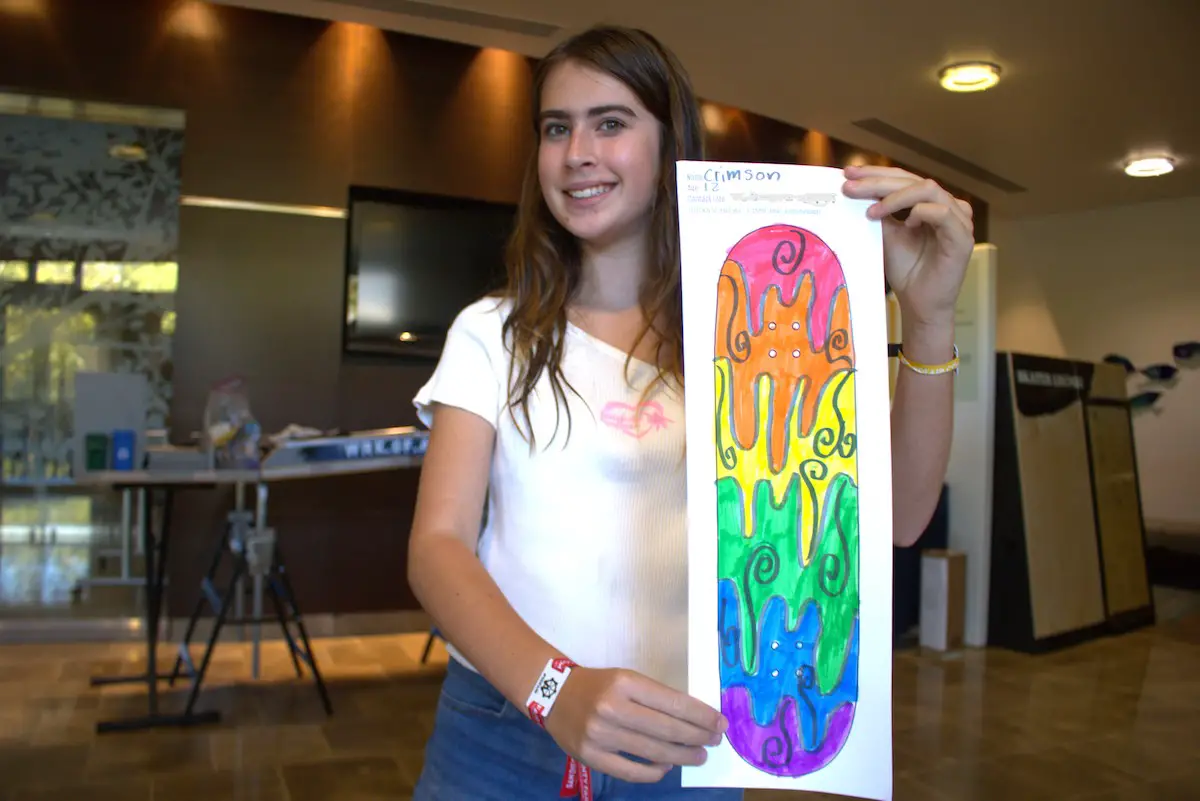 A girl holding up a skate deck design
