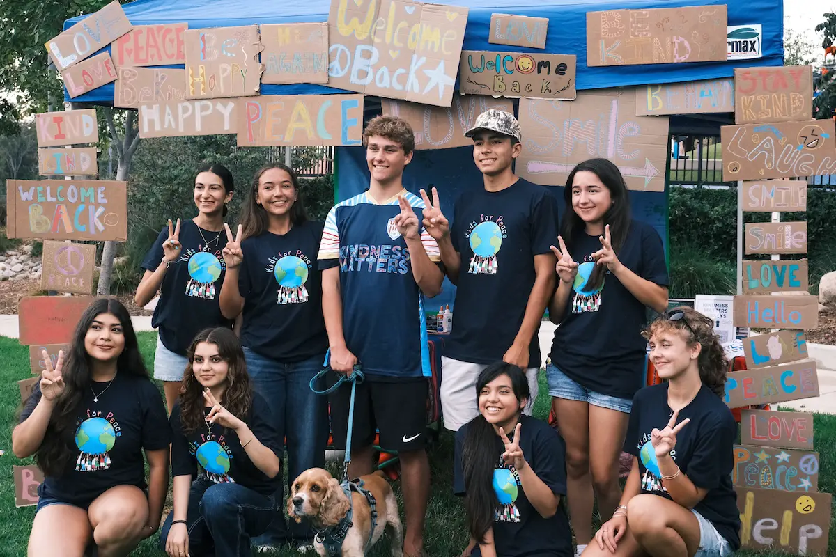 Kids for Peace interns pose in front of their booth where they led an activity for kids to create “Welcome Back” signs in anticipation of the new school year. Photo Courtesy of Nadia Razzaq