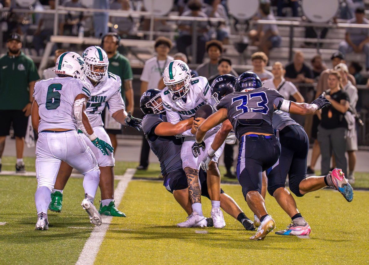 A swarm of Carlsbad High School defenders tackle the Pirates quarterback Anthony Barquinero on Friday in Oceanside. Photo by Jennifer Sanders