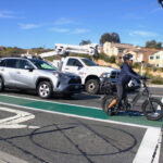 An e-bike rider waits alongside vehicle traffic at a stoplight on Encinitas Boulevard in 2024. File photo/Leo Place