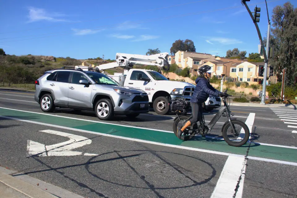 An e-bike rider waits alongside vehicle traffic at a stoplight on Encinitas Boulevard in 2024. File photo/Leo Place
