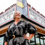 New Village Arts founder and Executive Artistic Director Kristianne Kurner stands in front of the Dea Hurston New Village Arts Center marquee in Carlsbad Village. Courtesy photo/NVA