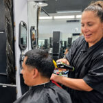 Sara Llames, owner of Knuckleheads Barber Shop in Oceanside, gives a customer a haircut at the shop. Photo by Patrick Howell