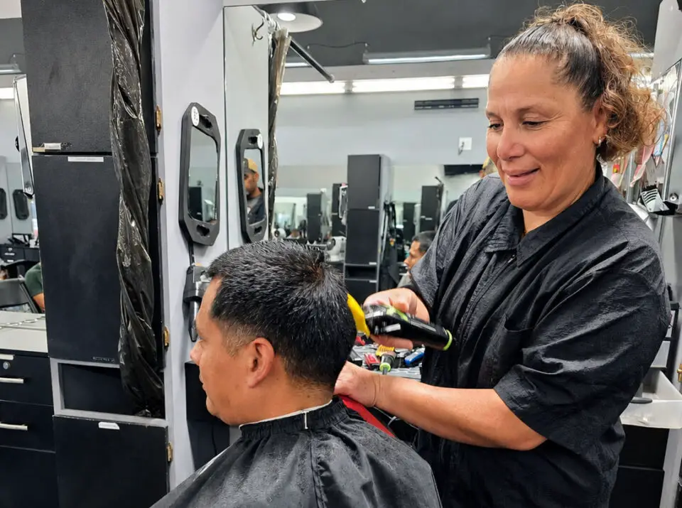 Sara Llames, owner of Knuckleheads Barber Shop in Oceanside, gives a customer a haircut at the shop. Photo by Patrick Howell