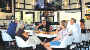 Tommy V’s spacious square bar anchors the brighter, airier new location and connects the indoor dining room with its climate-controlled indoor-outdoor patio. Photo by Rico Cassoni