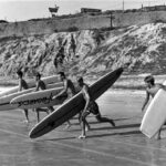 Surfers carry their boards toward the water during a 1965 paddle race in Del Mar. The city’s surfing heritage will take center stage at the inaugural Surf Del Mar Festival. Courtesy photo/Del Mar Historical Society