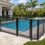 Black mesh safety fence installed around a residential backyard swimming pool.