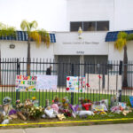 Flowers, handwritten notes and signs honoring the victims line the fence outside the Islamic Center of San Diego shortly after the May 18 mass shooting that killed three people. File photo/Leo Place