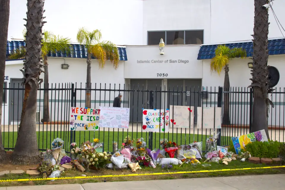 Flowers, handwritten notes and signs honoring the victims line the fence outside the Islamic Center of San Diego shortly after the May 18 mass shooting that killed three people. File photo/Leo Place