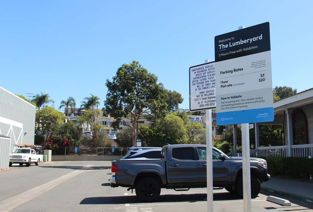 Proposed parking fees at The Lumberyard in Encinitas have drawn opposition from business owners and customers. New signs list rates starting at $3 for one hour and $20 for a flat rate valid until 11 p.m., with rates varying by demand. Photo by Jordan P. Ingram