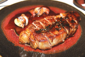 Medium rare dry-aged prime New York striploin was served with gold beet soubise, grilled onion glaze and smoked beet bordelaise. Photo by Rico Cassoni