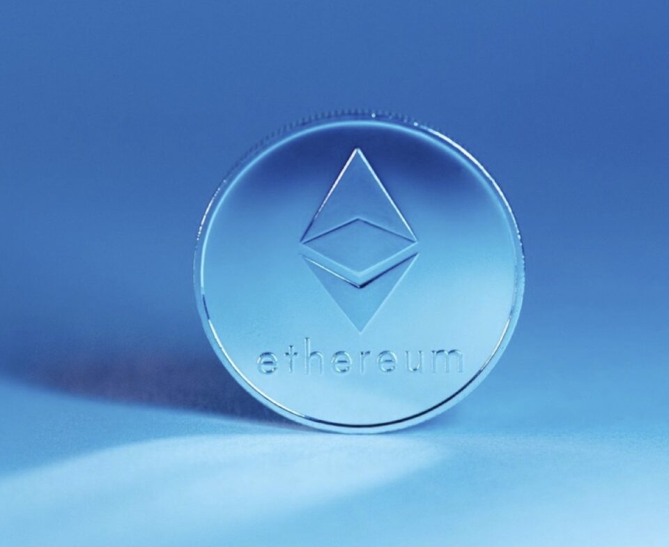 Physical Ethereum token standing upright against a blue background.