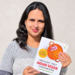 Uma Raghupathi, founder of Simple Sumptuous Cooking, holds her cookbook featuring plant-based Indian recipes. Courtesy photo