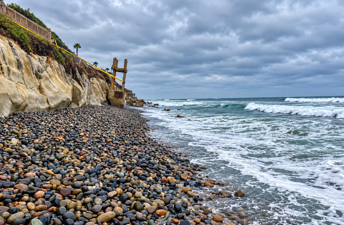 A narrow, cobble-covered shoreline in northern Leucadia, south of Ponto, where coastal erosion has left little sand along the base of the bluffs. Encinitas residents are proposing to recycle sand dredged from the San Dieguito Lagoon inlet to help replenish the city's northern beaches. Photo by Kathy Weldon