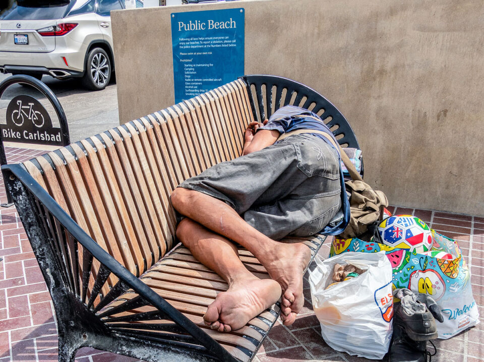 Homeless man sleeps on a bench in Carlsbad
