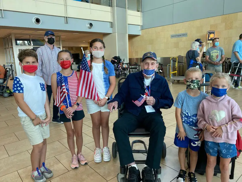 Rowe School student Sloan Harris greets World War II veteran Bob Brown at the airport alongside her brother Jake and classmates Elizabeth, Samantha and Dylan. 