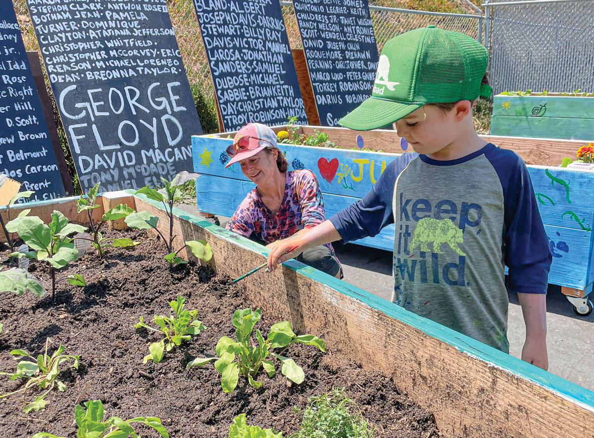 Local volunteers Lisa Elliot and her son Arthur finish painting one of several community garden beds at the Encinitas 4 Equality Multicultural Collective and Community Center along Coast Highway 101 in Encinitas